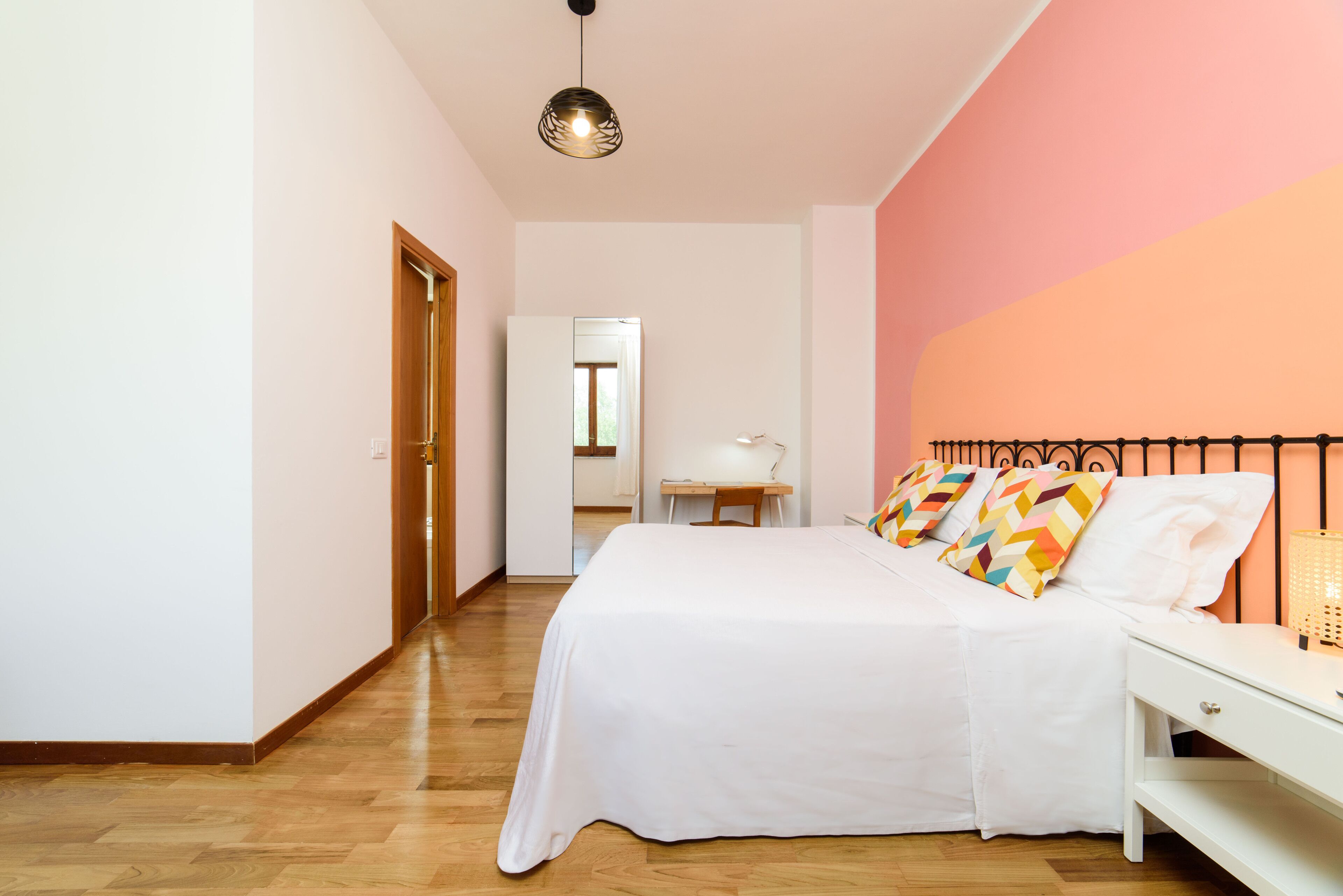 A bedroom with a bed, bedside table, and a desk.