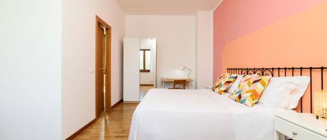 A bedroom with a bed, bedside table, and a desk.
