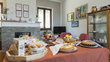Un coin repas avec une table mise pour le petit-déjeuner, comprenant des viennoiseries, du pain et des fruits.