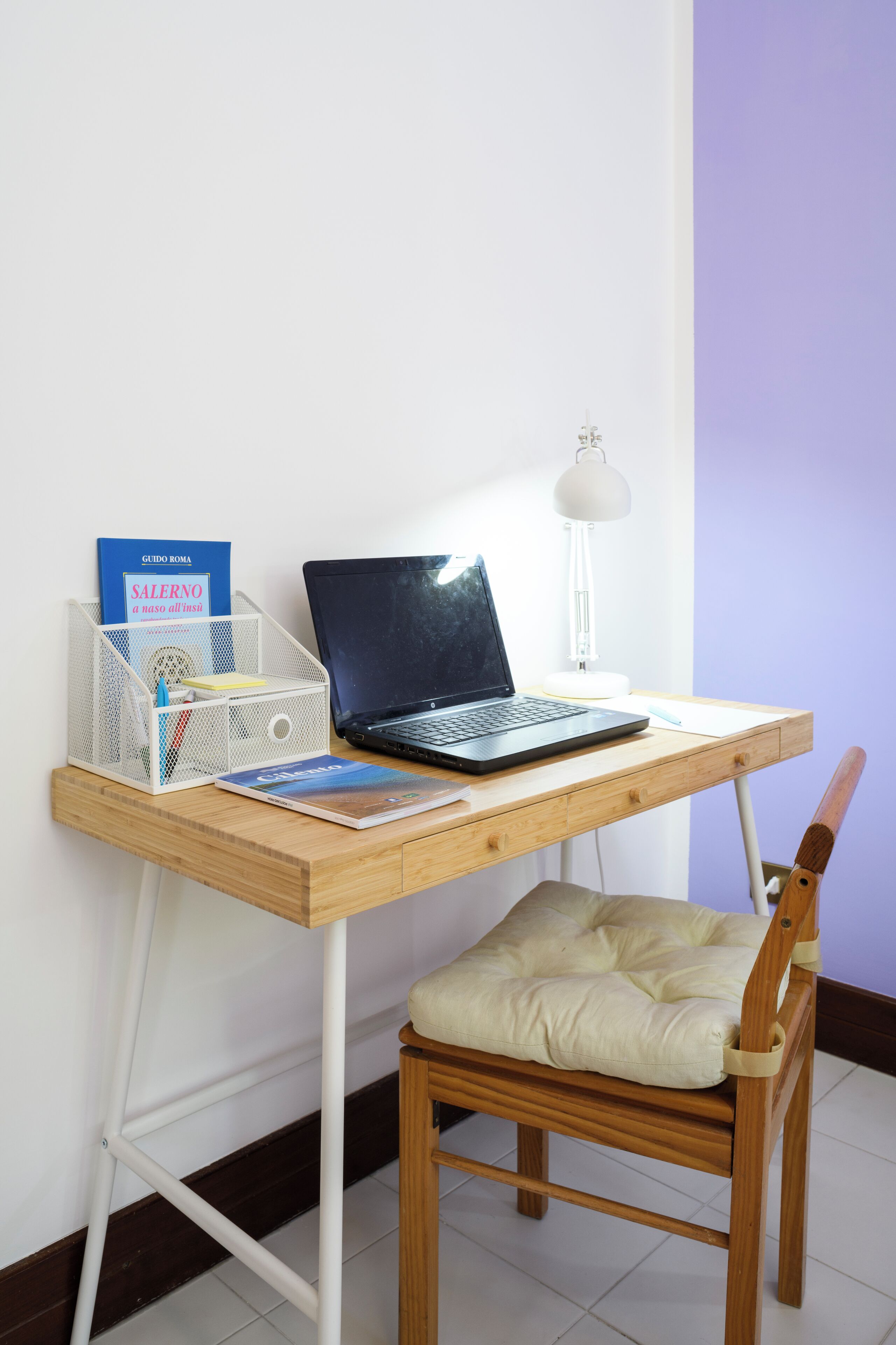 Un bureau en bois avec un ordinateur portable, une lampe et un livre.