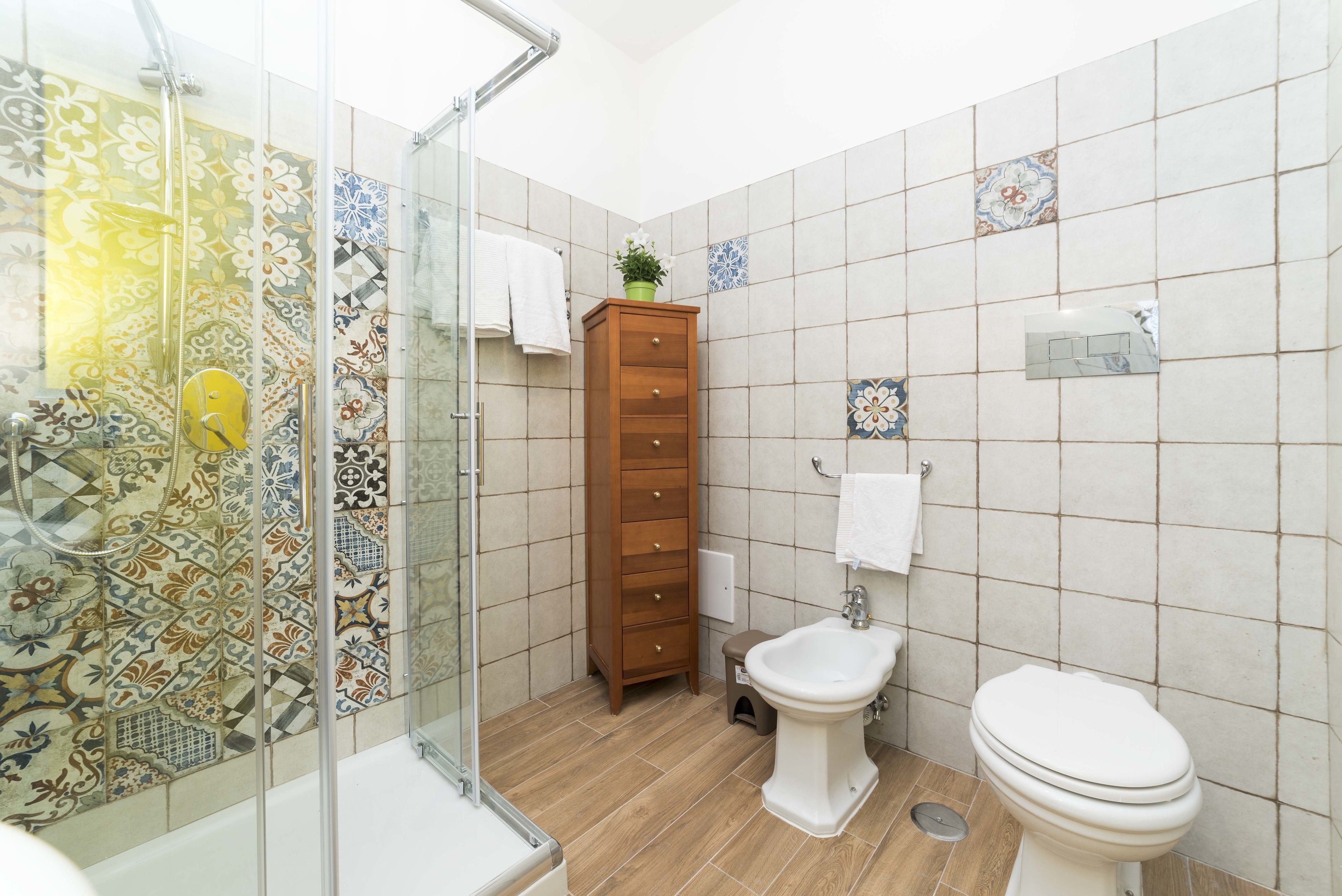 Ein Badezimmer mit Dusche, Toilette und einem Holzschrank.