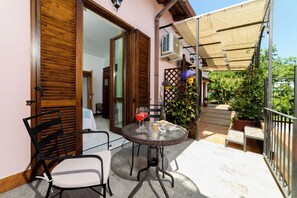 A patio with a table and chairs, a potted plant, and a wooden door. - Albachiara Casa Di Campagna B&B (Ogliastro Cilento)