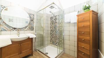 Un baño con ducha envuelta en vidrio, un armario de madera y un salpicadero de azulejos.