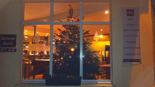 A Christmas tree in a window of a building with a sign reading "HG MENU ENTREE". - Hôtel de la Gare (Sainte-Gauburge-Sainte-Colombe)