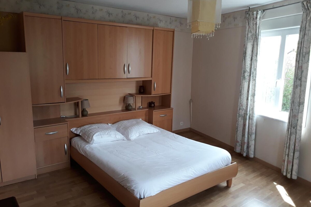 Un dormitorio con cama de madera, armario empotrado y ventana con cortinas.