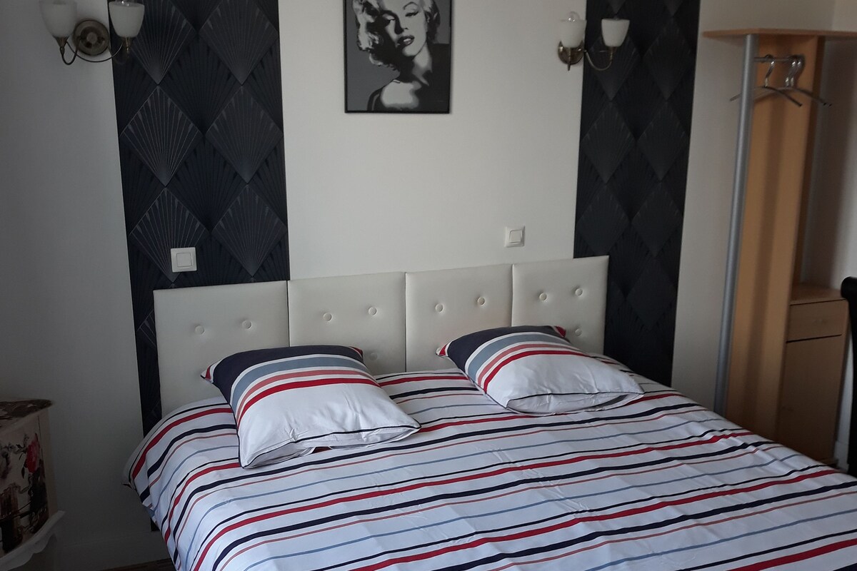 Una cama con ropa de cama a rayas, cabecera y un cuadro colgado en la pared.