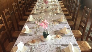 A long dining table set with plates, glasses, cutlery, and a centerpiece. - Hôtel de la Gare (Sainte-Gauburge-Sainte-Colombe)