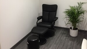 A room with a black massage chair, a small round ottoman, and a potted plant. - Hôtel de la Gare (Sainte-Gauburge-Sainte-Colombe)