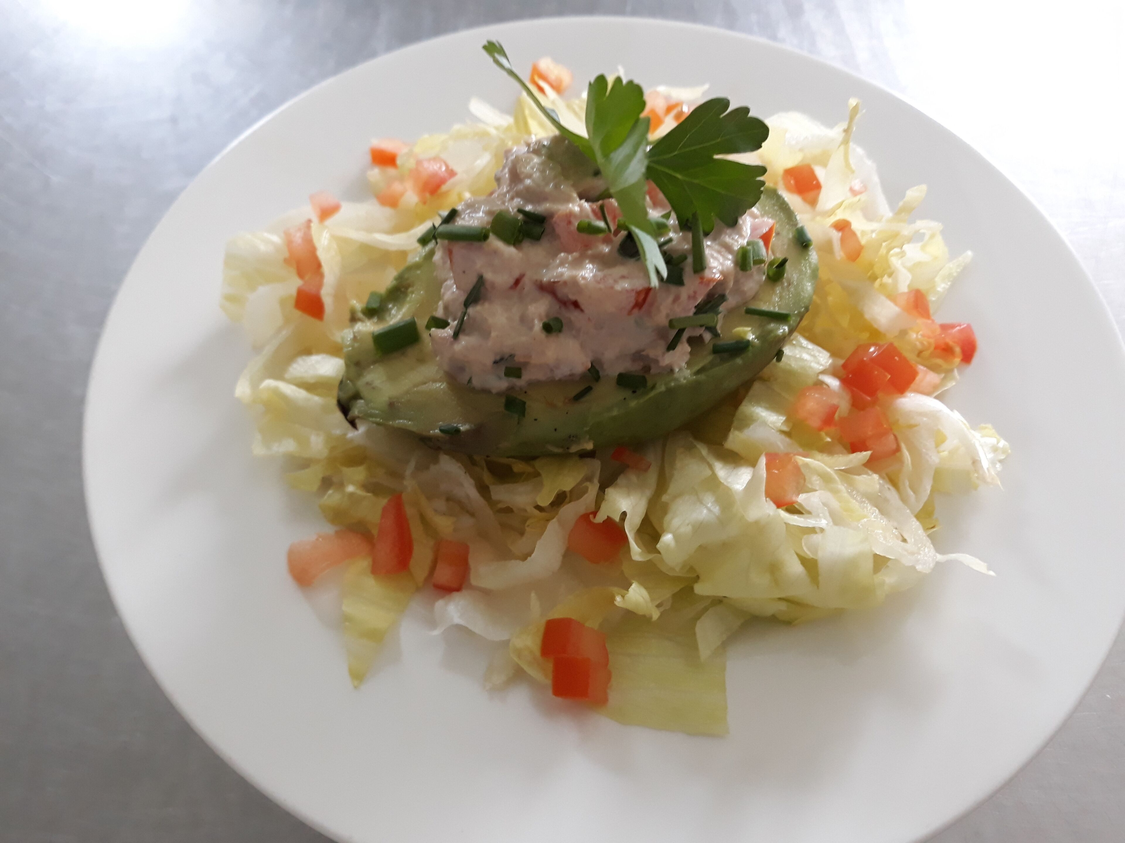 A plate with a stuffed pepper, shredded cabbage, diced tomatoes, and a garnish.