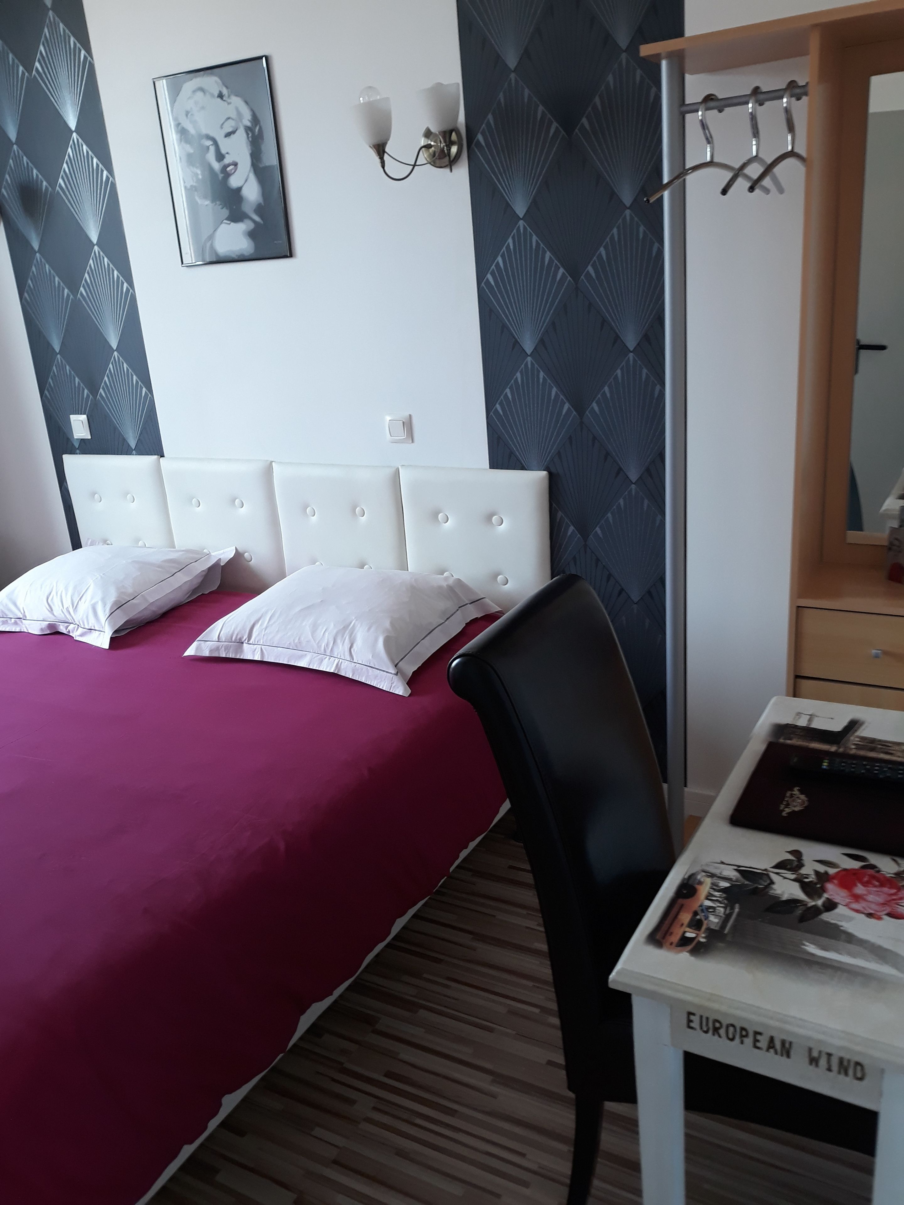 Een slaapkamer met een bed, een stoel, een bureau en een spiegel.