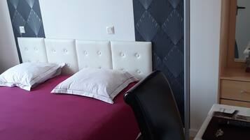 Ein Schlafzimmer mit einem Bett, einem Sessel, einem Schreibtisch und einem Spiegel.