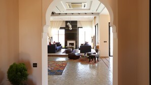 A spacious living room with a fireplace, sofas, and a coffee table. - Villa Zahoua (Marrakech)