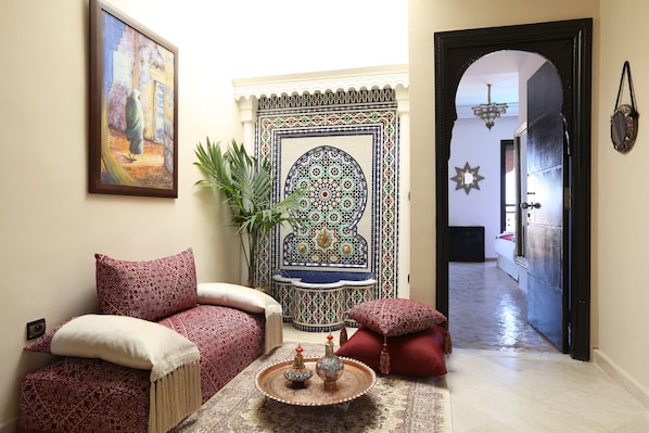A cozy living room with a sofa, pillows, a tray with decorative items, a large decorative door, and a hallway leading to another room.