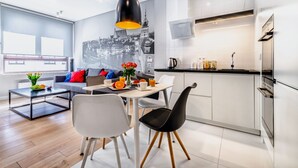 A modern kitchen with white cabinets, a black countertop, and a hanging pendant light. - Business Center Phoenix Apartments (Warsaw)