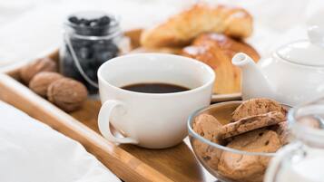 A tray with a cup of coffee, cookies, a croissant, and a teapot.