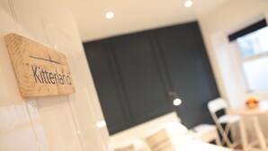 A room with a bed, a small table, and a chair. There is a sign on the wall that reads "Kitterland". - Carrick Rooms (Port St Mary)