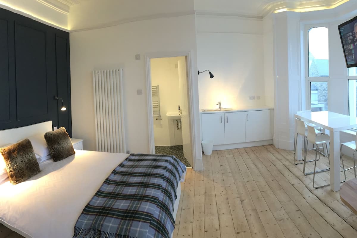 Ein Schlafzimmer mit Bett, Nachttisch und einem an der Wand befestigten Fernseher.