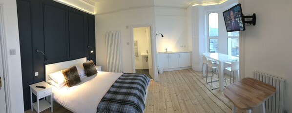 A bedroom with a bed, bedside table, and a TV mounted on the wall. - Carrick Rooms (Port St Mary)