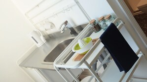 A kitchen with a sink, a kettle, a juicer, and a cutting board. - Carrick Rooms (Port St Mary)