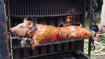 A whole roasted pig on a spit over an open flame.