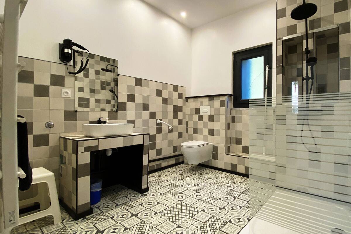 A modern bathroom with a tiled floor, a sink, a toilet, and a shower area.