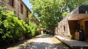 Un camí de grava estret flanquejat per vegetació exuberante i edificis de fusta.
