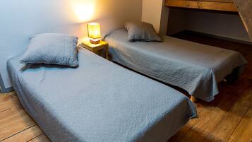 Two single beds with grey quilted covers, a bedside table, and a lamp.