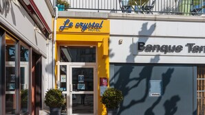 The exterior of Le Crystal Hotel with a yellow facade and a glass entrance. - Le Crystal Hôtel (Royan)