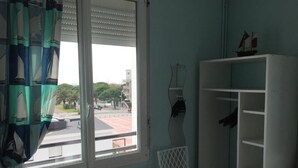 A room with a window, a chair, and a white shelving unit. - Le Crystal Hôtel (Royan)