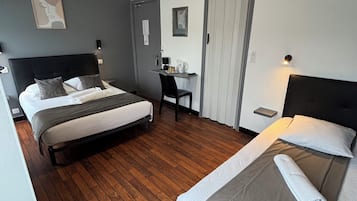 A hotel room with two beds, a desk, and a wardrobe.