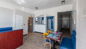 A modern kitchen with a wooden countertop and a built-in stove. There is a dining area with a table and chairs, and a blue bench. - Le Crystal Hôtel (Royan)