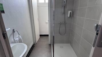 Une salle de bain moderne avec une douche à parois de verre, un lavabo blanc et un porte-serviettes.