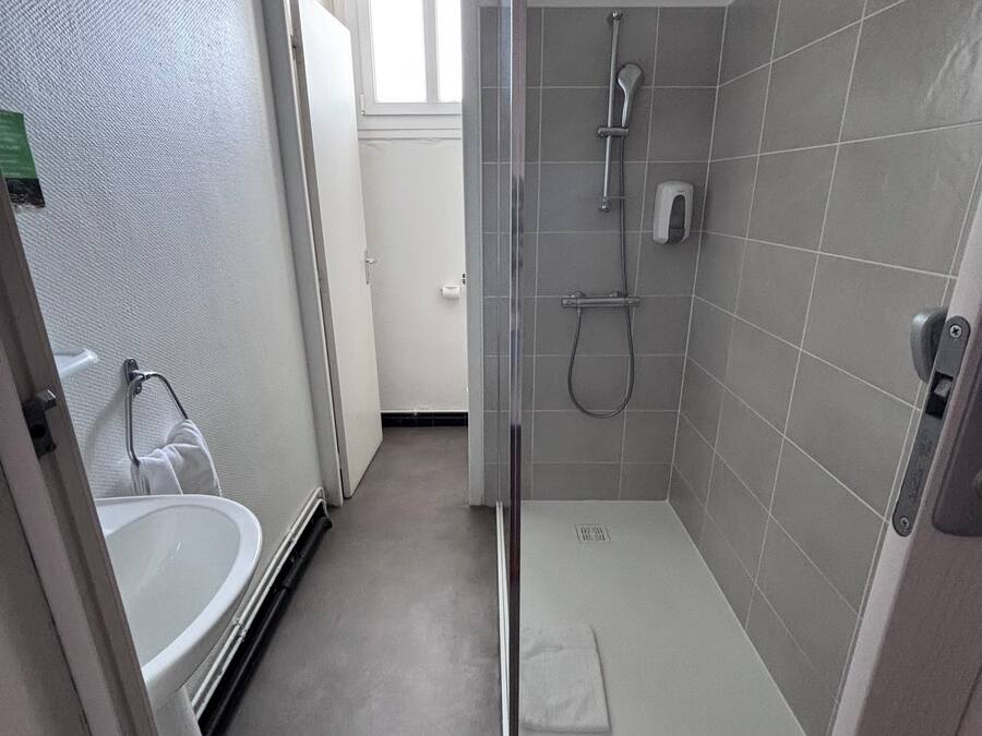 Une salle de bain moderne avec une douche à parois de verre, un lavabo blanc et un porte-serviettes.