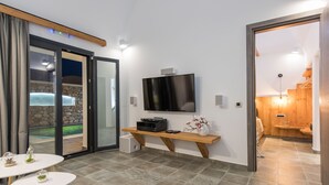 A modern living room with a flat-screen TV, a wooden bench, and a small table with decorative items.