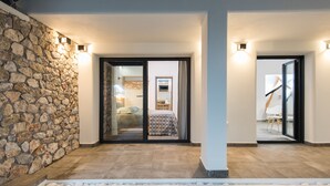 A modern interior with a stone wall, a pool, and a bedroom visible through glass doors.