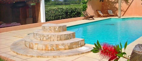 Una piscina al aire libre, sombrillas, sillones reclinables de piscina
