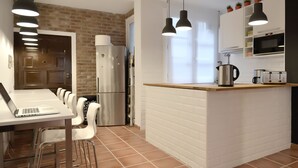 Una cocina moderna con salpicadero de ladrillo blanco, electrodomésticos de acero inoxidable, una isla de madera e iluminación colgante.