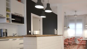 Cocina moderna con armarios blancos, encimera de madera y salpicadero negro. Tres lámparas colgantes sobre la encimera.