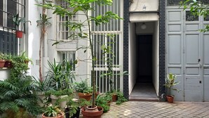 A courtyard with potted plants, a gated entrance, and a tiled floor.