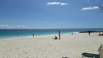 På stranden, hvidt sand, liggestole, parasoller