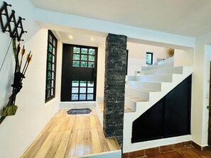 Ein modernes Interieur mit Holzboden, einer schwarzen Tür und einer weißen Treppe.