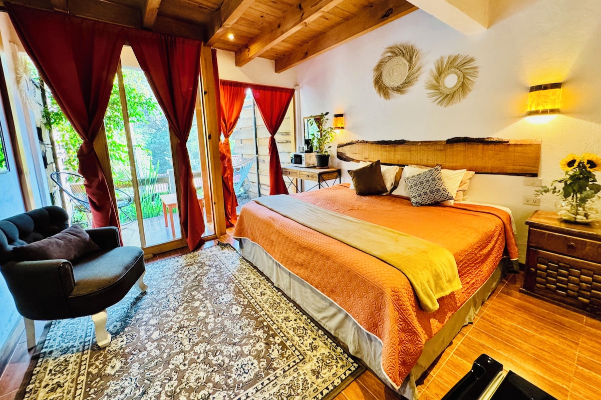 Quarto com cama, poltrona, tapete e vista para o exterior.