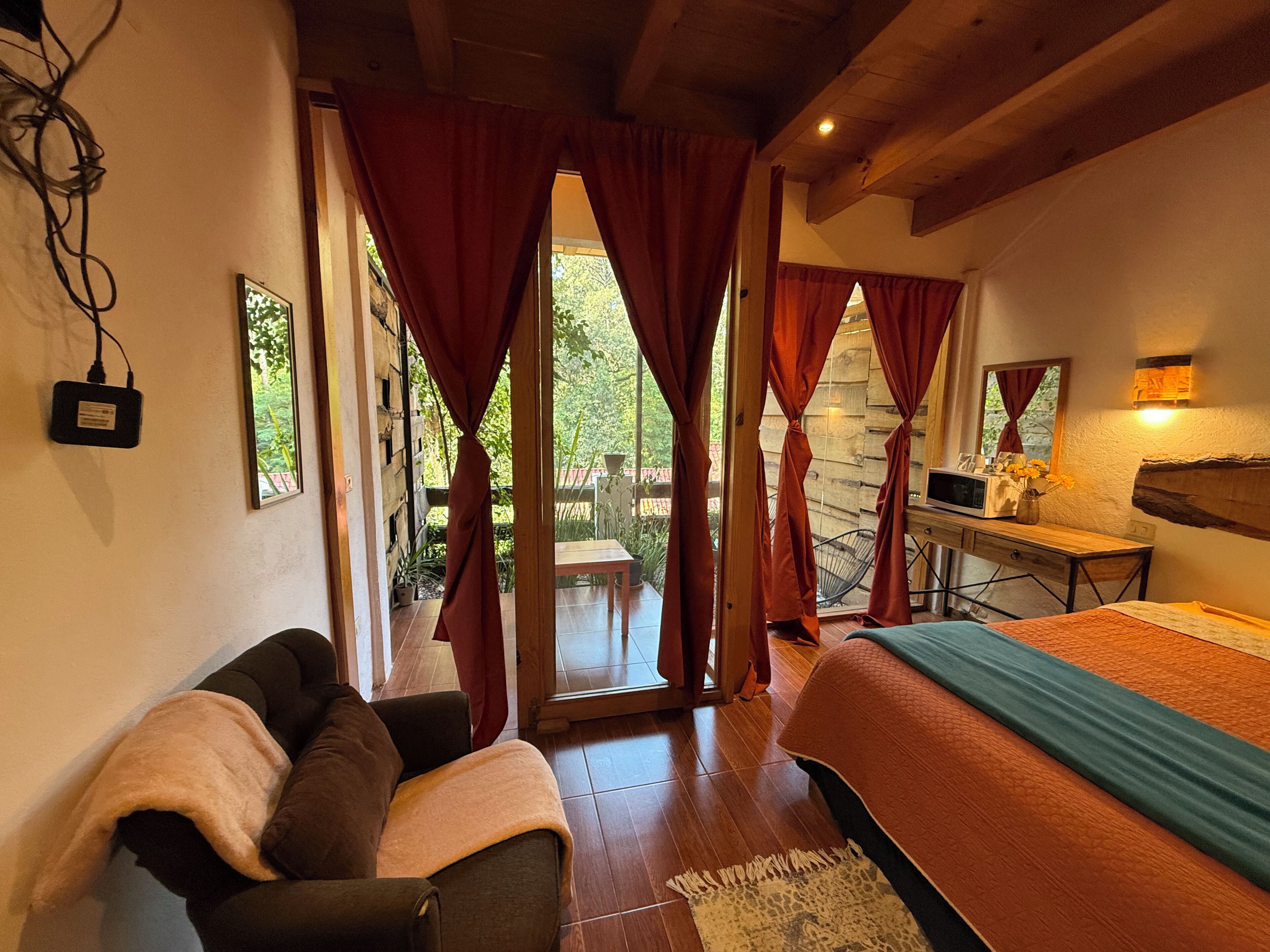 Una habitación con cama, escritorio, silla y ventana con cortinas.