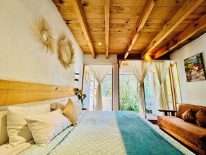 A bedroom with a wooden ceiling, a bed with a quilt, a sofa, and a painting on the wall. - Encino House Hotel & Glamping Valle de Bravo (Valle de Bravo)
