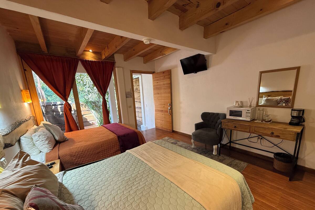 Una camera da letto con due letti, una scrivania con un forno a microonde, una sedia e una TV appesa al muro.