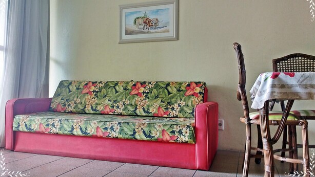 A room with a floral sofa, a wooden chair with a table, and a painting on the wall. - Canascenter Apart Hotel (Florianópolis)