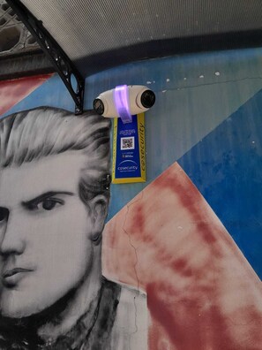 Una pared con un código QR, un patrón geométrico azul y rojo, y una parte del cabello de una persona.