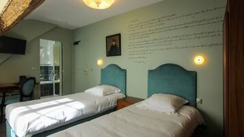 A bedroom with two beds, a desk, and a chair.
