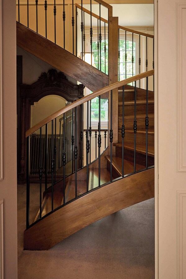 A wooden staircase with black railings and a curved design. - Château Du Bois Guibert (Bonneval)