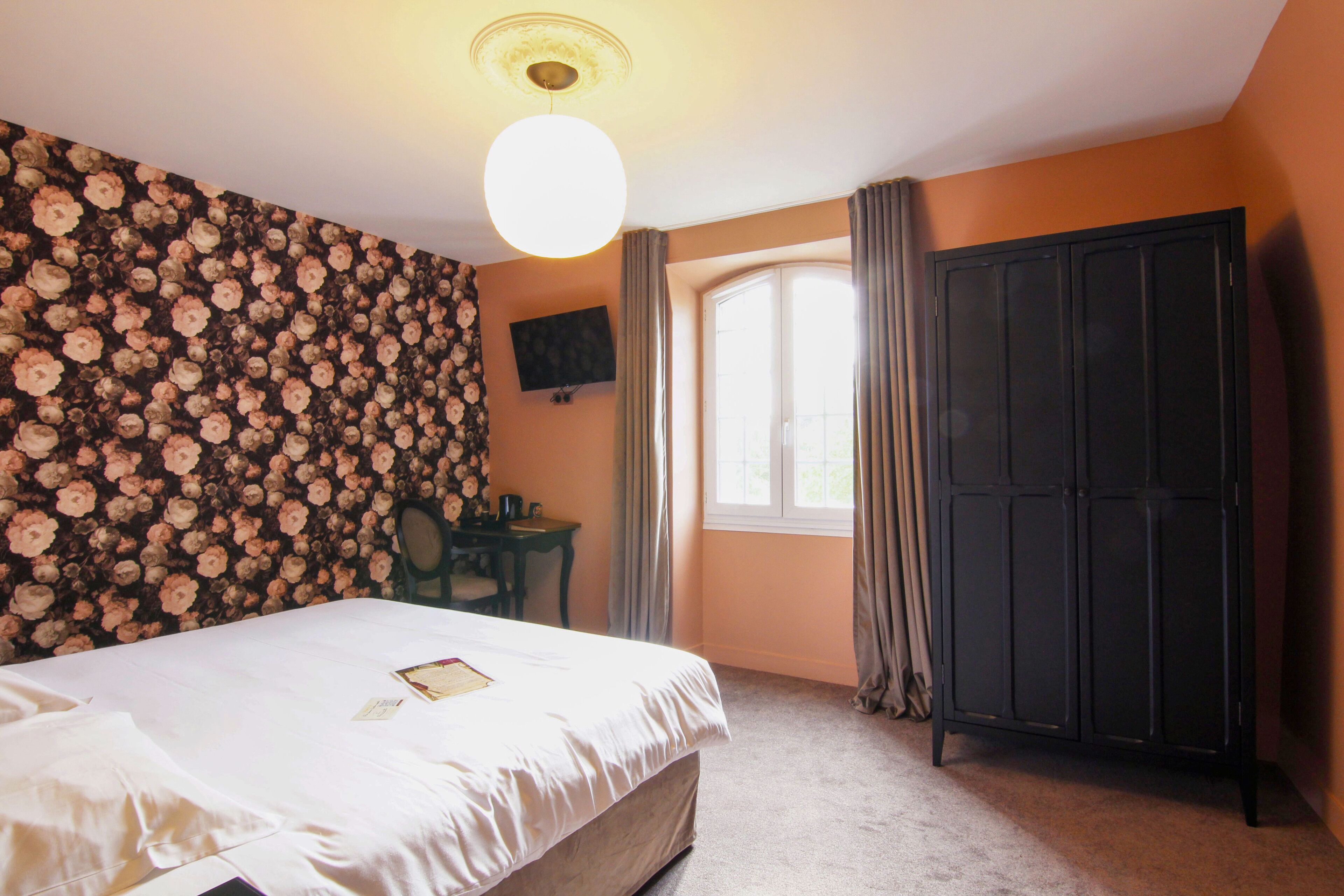 Un dormitorio con cama, escritorio, armario y ventana con cortinas.